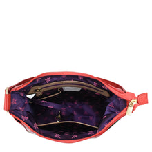 Load image into Gallery viewer, Open Anuschka Classic Hobo With Side Pockets - 382 with a genuine leather red exterior and a purple interior featuring a floral pattern, displayed against a white background.

