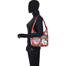 Load image into Gallery viewer, A mannequin wearing black attire and showcasing a floral print red Classic Hobo With Side Pockets - 382 handbag by Anuschka with a shoulder strap.
