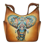 The Anuschka Classic Hobo With Side Pockets - 382 showcases a hand-painted, intricately designed, colorful elephant head in the center of the front panel. The elephant features elaborate patterns and details, while the bag also includes two small side pockets.