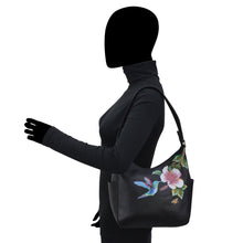 Load image into Gallery viewer, Woman in a black turtleneck showcasing a Anuschka Classic Hobo With Side Pockets - 382 handbag with floral embroidery on the shoulder strap.
