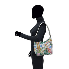 Load image into Gallery viewer, A mannequin wearing a black turtleneck and pants carries an Anuschka Classic Hobo With Side Pockets - 382 handbag with a genuine leather shoulder strap on its shoulder.
