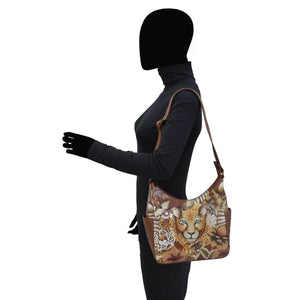 Side profile of a person modeling an Anuschka Classic Hobo With Studded Side Pockets - 433 leather shoulder bag with a leopard print design.
