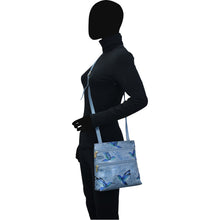 Load image into Gallery viewer, Person with a silhouette face wearing a black leather outfit and carrying an Anuschka Medium Crossbody With Double Zip Pockets - 447 with an adjustable strap and zebra pattern.
