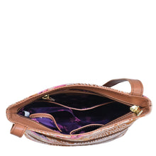 Load image into Gallery viewer, Open Anuschka genuine leather brown bag with purple interior showing contents inside, featuring an adjustable shoulder strap.
