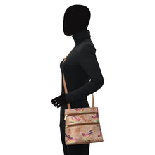 Load image into Gallery viewer, Side profile of a mannequin wearing a black turtleneck and gloves, carrying an Anuschka Medium Crossbody With Double Zip Pockets - 447 with an adjustable strap.
