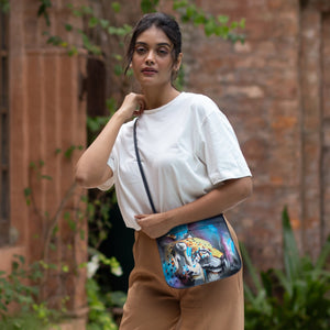 Woman carrying a Anuschka Slim Crossbody With Front Zip - 452 with a colorful design, walking outdoors.