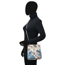 Load image into Gallery viewer, A silhouette of a person wearing a turtleneck and carrying a dark forest green, floral-patterned Anuschka Slim Crossbody With Front Zip - 452 made of genuine leather.
