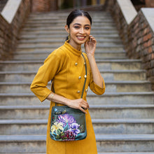 Load image into Gallery viewer, A woman in a yellow outfit with a hand-painted, Anuschka Slim Crossbody With Front Zip - 452 genuine leather mini crossbody purse smiles on steps.
