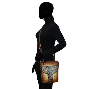 Side view of a mannequin wearing a black turtleneck and gloves, accessorized with an Anuschka Organizer Crossbody With Extended Side Zipper - 493 featuring a hand painted elephant design.