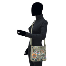 Load image into Gallery viewer, Mannequin displaying an Anuschka Expandable Travel Crossbody - 550 with floral design and an adjustable strap.
