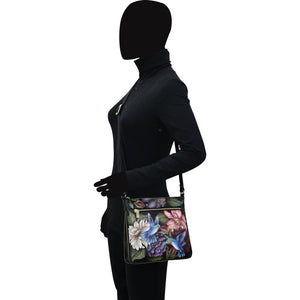 Mannequin dressed in black outfit with an Anuschka Expandable Travel Crossbody - 550 featuring an adjustable shoulder strap.