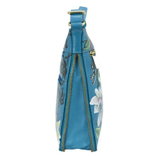Load image into Gallery viewer, Side view of a blue floral print, genuine leather Anuschka handbag with a zipper closure.

