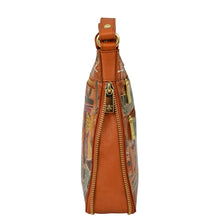 Load image into Gallery viewer, Side view of the Anuschka Expandable Travel Crossbody - 550, featuring a gold zipper and exquisite hand-painted artwork on genuine leather.
