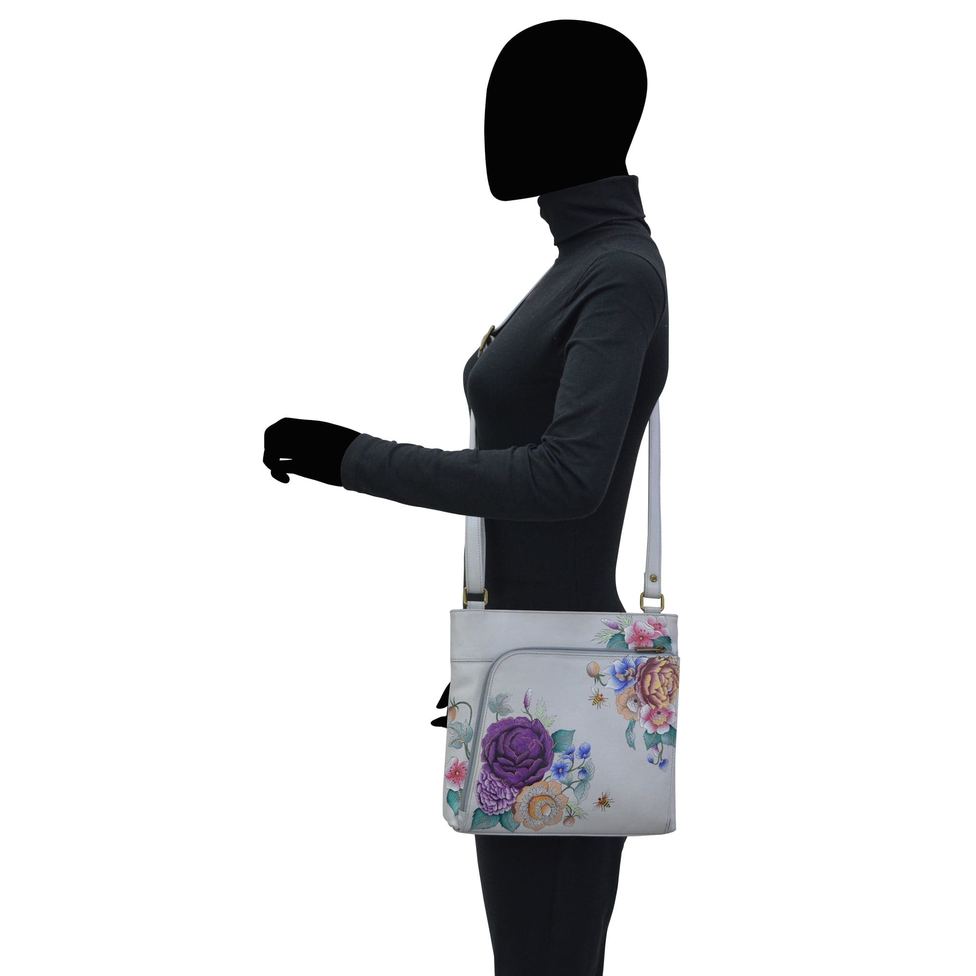 Mannequin displaying a leather Anuschka crossbody shoulder bag with floral design, featuring an adjustable strap.