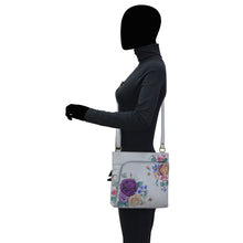 Load image into Gallery viewer, Mannequin displaying a leather Anuschka crossbody shoulder bag with floral design, featuring an adjustable strap.
