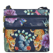 The Anuschka Crossbody With Front Zip Organizer - 651 is a navy blue handbag adorned with hand-painted flowers, butterflies, and leopards for a floral and jungle-themed design. It features an adjustable crossbody strap, two front zippered pockets, and a flap-over style with an RFID protected organizer.