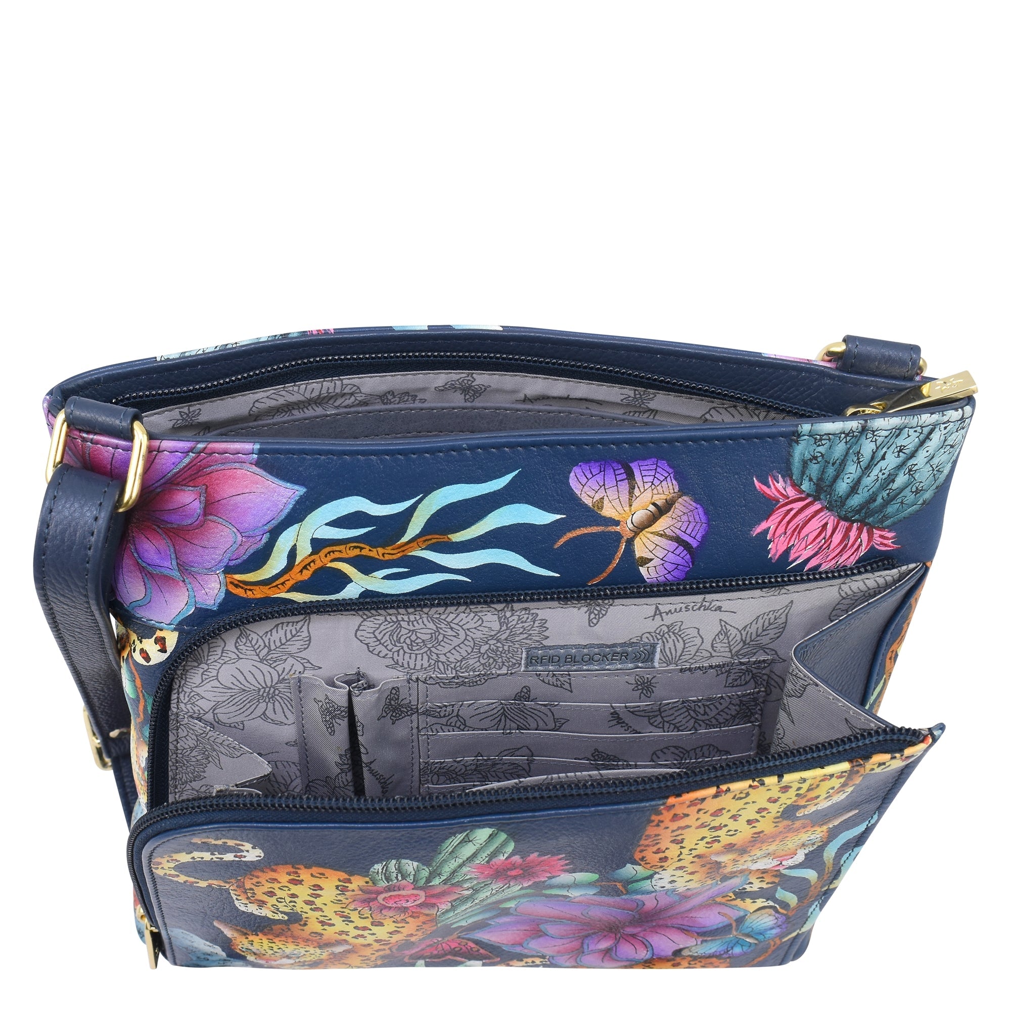 The Anuschka Crossbody With Front Zip Organizer - 651 is a blue hand-painted leather handbag adorned with a unique floral and leopard print design. Inside, you'll find a grey interior featuring multiple pockets, intricate patterns, and an RFID protected organizer. For added convenience, the bag includes an adjustable crossbody strap.