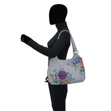 Load image into Gallery viewer, A person with a black silhouette for a head wearing a long sleeve shirt and carrying an Anuschka Triple Compartment Large Satchel - 652 with multiple pockets.
