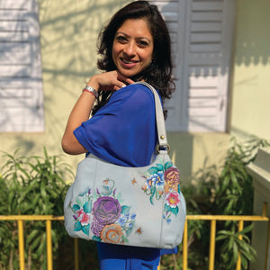 Woman smiling while holding an Anuschka Triple Compartment Large Satchel - 652 with multiple pockets over her shoulder.