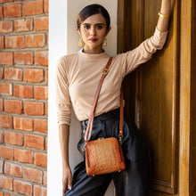 Load image into Gallery viewer, A woman posing with an Anuschka Zip Around Travel Organizer - 668 against a brick wall.
