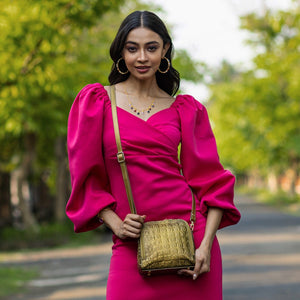 A woman in a vibrant pink dress with puff sleeves, carrying an Anuschka Zip Around Travel Organizer - 668, walking outdoors.