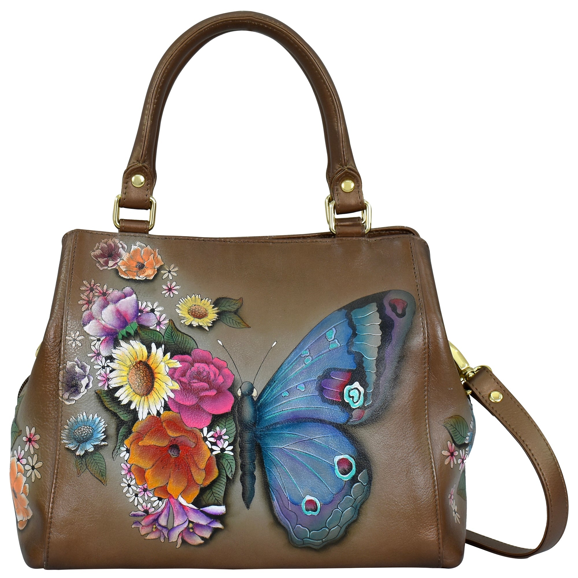 The Anuschka Multi Compartment Satchel - 690 is a brown handbag with brass hardware, showcasing a large, colorful hand-painted butterfly and floral design on the front. It has a structured shape with two handles and an adjustable detachable shoulder strap made from genuine leather.