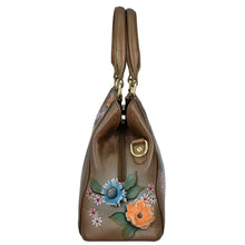 Load image into Gallery viewer, Side view of the Anuschka Multi Compartment Satchel - 690 in brown genuine leather with a floral print, featuring hand-painted blue and orange flowers, dual handles, and an adjustable shoulder strap.
