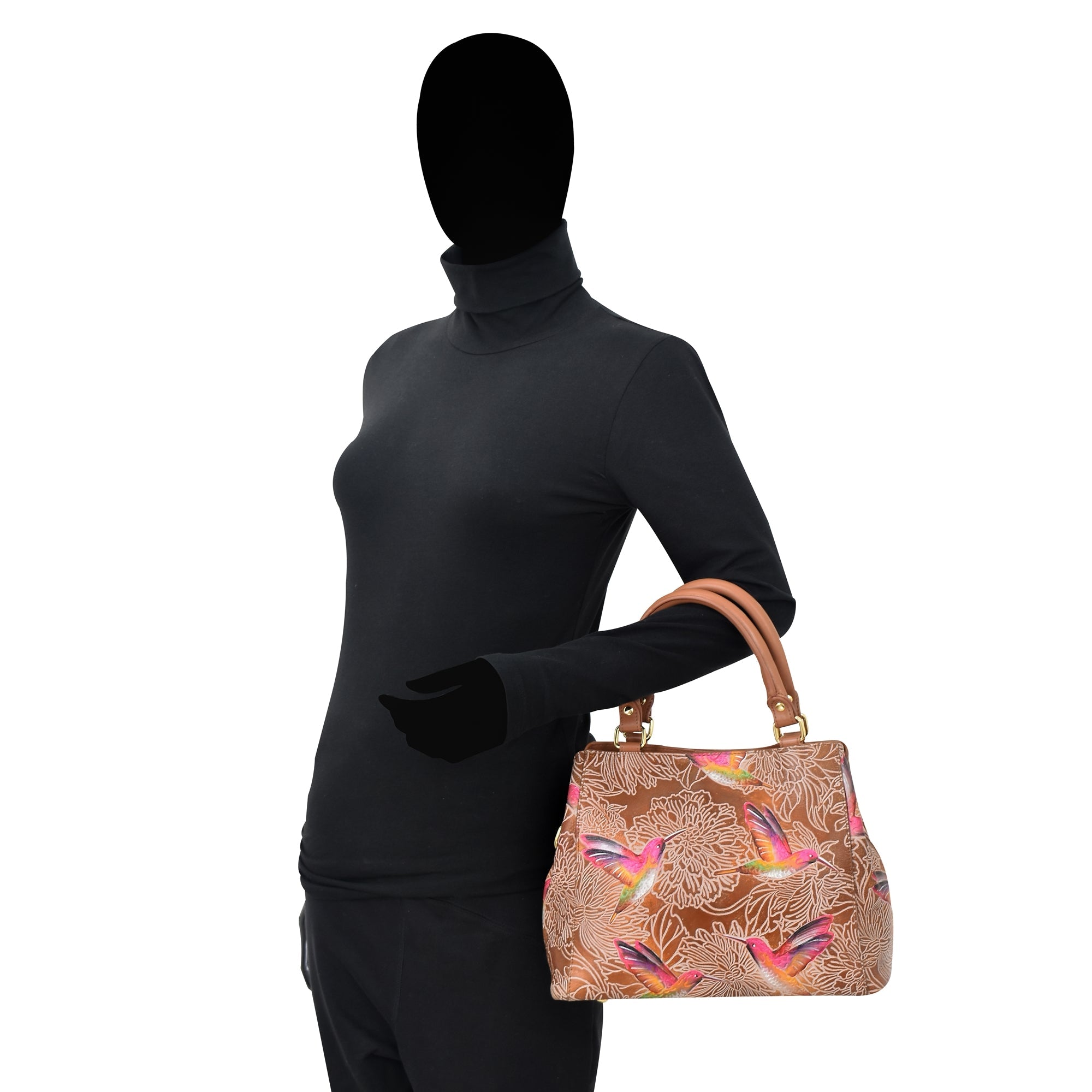 Silhouette of a person in a fitted black turtleneck holding an Anuschka Multi Compartment Satchel - 690 with genuine leather exterior, adorned with colorful floral and bird designs.