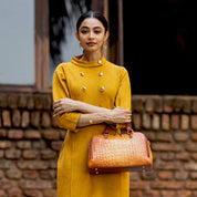 A woman in a mustard yellow dress with a textured brown Anuschka Wide Organizer Satchel - 695.