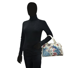 Load image into Gallery viewer, Mannequin dressed in a black turtleneck and gloves holding a Anuschka Wide Organizer Satchel - 695 with colorful bird designs.
