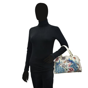 Mannequin dressed in a black turtleneck and gloves holding a Anuschka Wide Organizer Satchel - 695 with colorful bird designs.