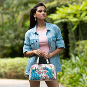 Woman holding a Anuschka Wide Organizer Satchel - 695 wearing a denim jacket outdoors.