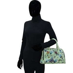 Mannequin dressed in a black outfit holding a floral-patterned, Anuschka Wide Organizer Satchel - 695.