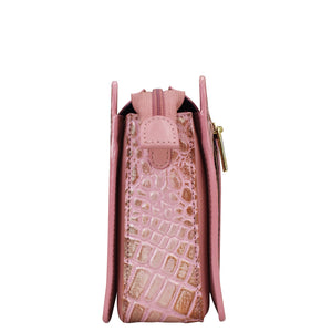 Side view of a pink crocodile texture Anuschka Triple Compartment Crossbody - 696 handbag with gold zipper detail and organized compartments.