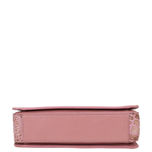 Side view of a pink, organized Triple Compartment Crossbody - 696 by Anuschka with a textured design and compartments.