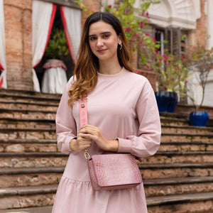 Woman dressed in pink posing with an organized Anuschka Triple Compartment Crossbody - 696 on steps.