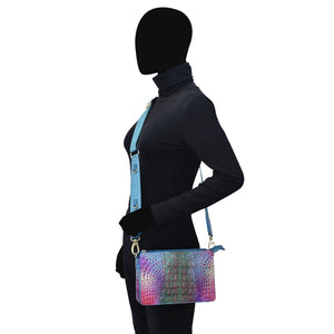 Person wearing a black outfit and a multicolored Anuschka Triple Compartment Crossbody - 696 bag, standing side-on with a silhouette for a head.
