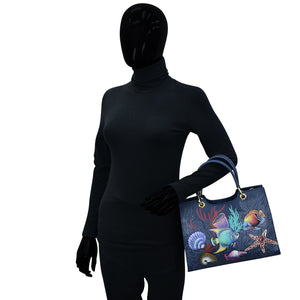 Mannequin dressed in black with a colorful fish-themed Anuschka Medium Satchel - 697.