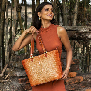 Woman smiling and posing with an Anuschka Large Zip Top Tote - 698 outdoors.