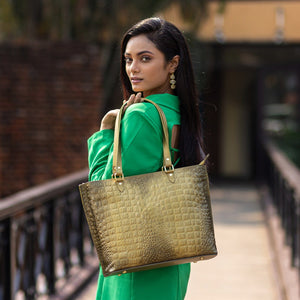 A woman in a green outfit carrying a large textured, genuine leather Anuschka Large Zip Top Tote - 698.