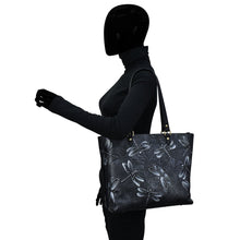Load image into Gallery viewer, A silhouette of a person carrying an Anuschka Large Zip Top Tote - 698 with a hand-painted floral pattern.
