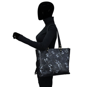 A silhouette of a person carrying an Anuschka Large Zip Top Tote - 698 with a hand-painted floral pattern.