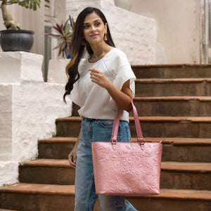 Woman standing on steps holding a pink leather Large Zip Top Tote - 698 by Anuschka.