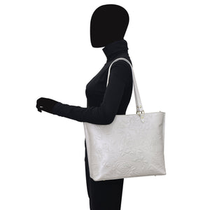 A person with a black silhouette profile carrying a Anuschka Large Zip Top Tote - 698 on their shoulder.