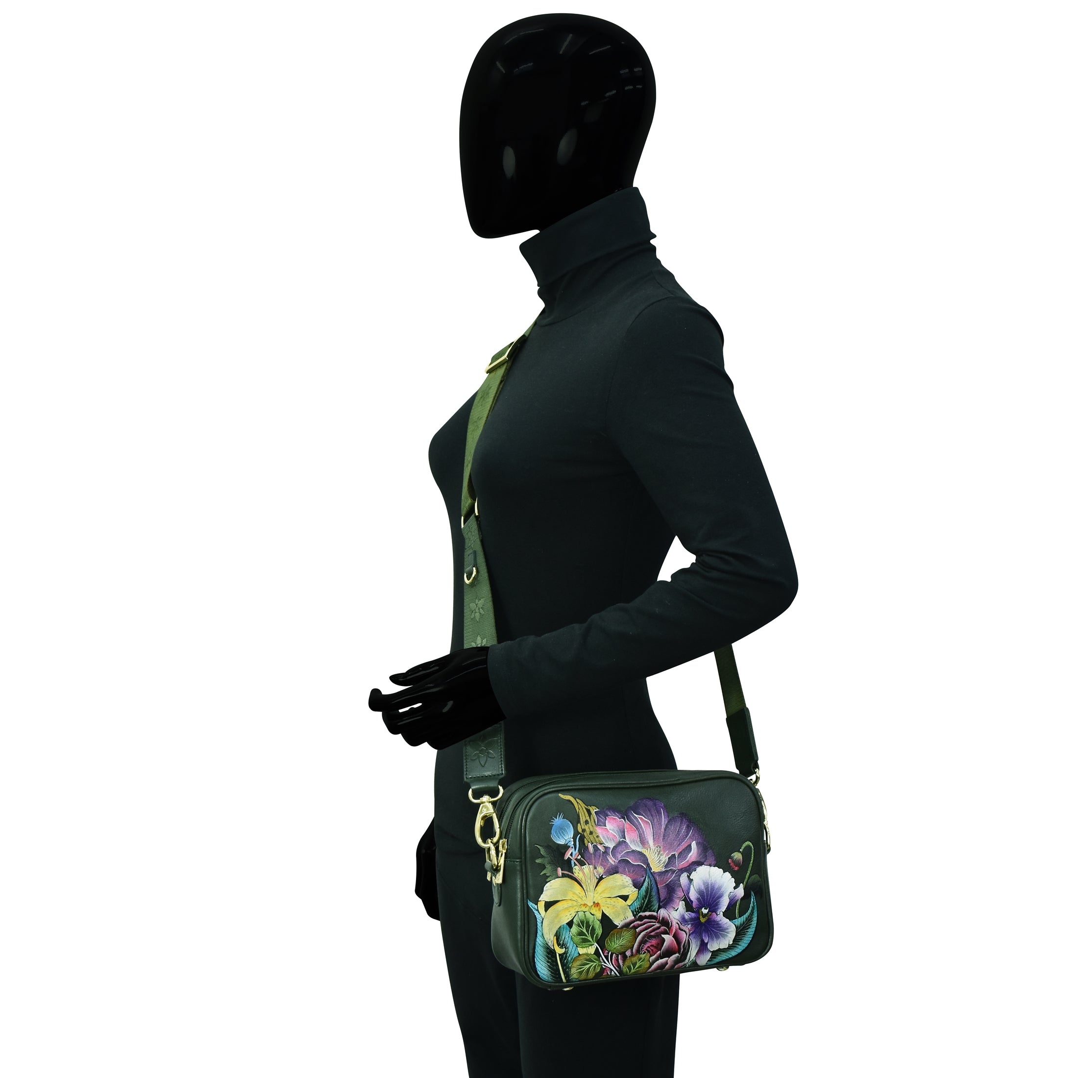 A mannequin dressed in a black outfit with a crossbody floral handbag featuring an Anuschka Twin Top Messenger - 704 RFID protected card case.