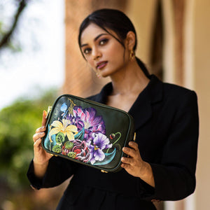 Woman showcasing an Anuschka Twin Top Messenger - 704 purse with RFID protection and a floral pattern.