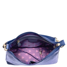 Load image into Gallery viewer, Open Anuschka blue leather hobo with chain strap 707 bag with purple interior showing empty compartments and a floral pattern.
