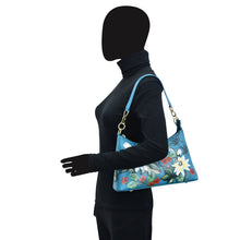 Load image into Gallery viewer, Mannequin displaying a blue floral Anuschka genuine leather hobo bag with chain strap.
