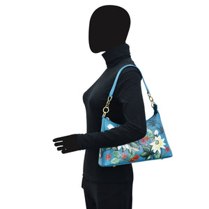 Mannequin displaying a blue floral Anuschka genuine leather hobo bag with chain strap.