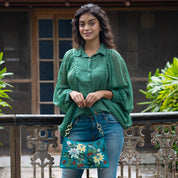 Woman standing by a railing with an Anuschka Hobo With Chain Strap - 707 purse.